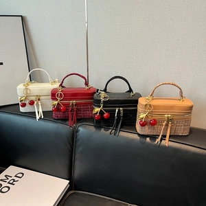 Detail of four colorful square handbags featuring tweed stitching and cherry charms