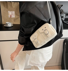 Dettaglio della borsa a tracolla color crema con doppie tasche con fibbia su modella
