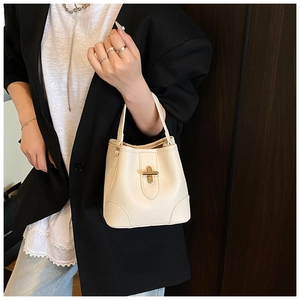 Close-up of creamy white bucket bag featuring grainy leather and gold twist lock detail
