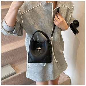 Chic black litchi grain bucket bag with gold lock buckle crossbody on gray hoodie