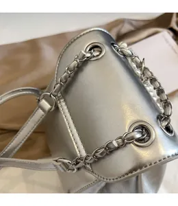 Close-up of metallic silver bag with chunky chain strap and pearl handle on satin background