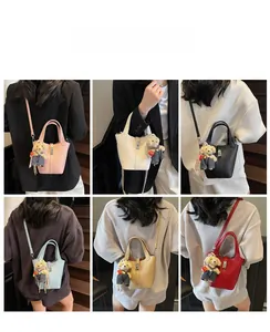 Close-up of leather bucket bags with bear charms in pink, white, blue, and black
