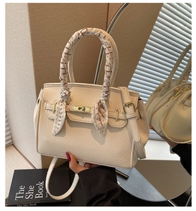 Close-up of cream pebble leather handbag with gold twist lock and patterned silk scarf
