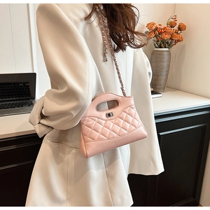 Detailed view of light pink quilted crossbody bag with metal twist lock and chain strap