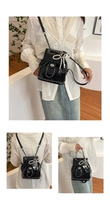 Detail view of mini black backpack featuring pearl bow and metallic heart charm