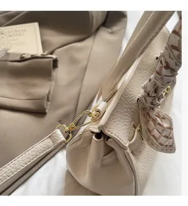 Close-up of cream lychee leather handbag with gold hardware and elegant silk scarf detail