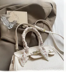 Detail of off-white lychee texture leather bag with silk scarf handle and gold buckle