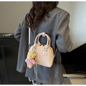 Vista dettagliata di una mini borsa Boston rosa con un simpatico ciondolo orsetto di peluche.