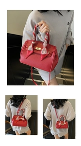 Detail of red lychee leather handbag with a gold lock and decorative handle scarf