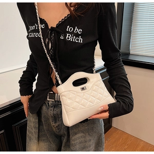 Détail d'un sac bandoulière blanc matelassé avec chaîne argentée et poignée haute