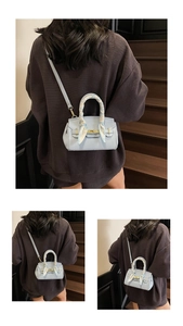 Detailed view of a light blue textured leather handbag with a silk scarf handle and gold clasp