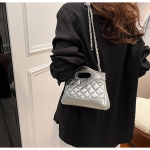Detail of silver quilted chain bag worn by model showing its side profile and texture