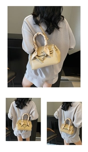 Detail of beige lychee leather handbag featuring gold clasp and silk scarf wrapped handle