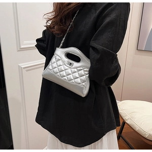 Borsa trapuntata argento indossata da modella con tracolla e manico metallico
