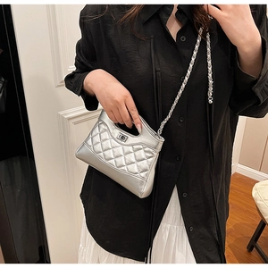 Detail of silver quilted handbag featuring metallic finish and turn-lock chain strap
