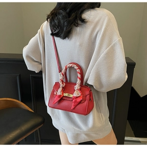 Detail of red lychee grain leather handbag with printed silk scarf handle and metal lock