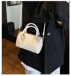 Dettaglio della borsa Boston in pelle lucida bianca con logo a rilievo e ciondolo