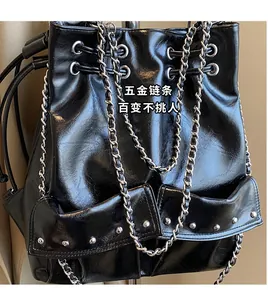 Detail of glossy black bucket bag featuring heavy metal chain strap and rivet pockets
