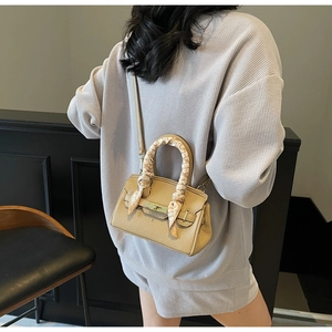 Detail of khaki leather handbag with floral scarf handle decoration and metal buckle