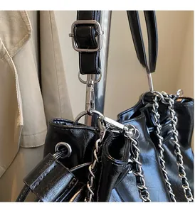 Detail of glossy black bucket bag featuring silver metal chain and adjustable hook buckle