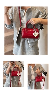 Dettaglio borsa Boston in pelle verniciata rossa con logo goffrato e ciondolo