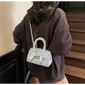 Detail of light blue lychee leather handbag with golden lock and silk scarf on handle