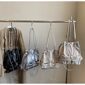 Detail of four bucket bags in black, silver, and beige with metal chains and rivets