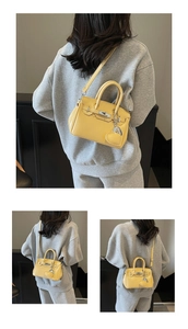 Detail of a bright yellow textured leather mini handbag with a heart charm and strap