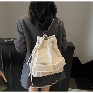 Detail of cream white leather bucket backpack with silver chain straps and rivet pockets
