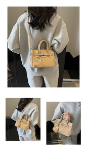 Close-up of khaki mini Kelly style handbag featuring silver buckle and heart charm details