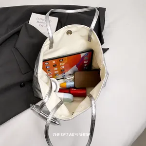 Geräumiges Innere der silbernen Metallic-Tasche mit Magnetverschluss und Alltagsgegenständen