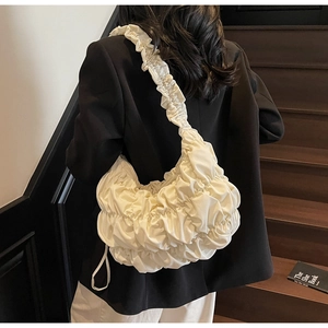 Close-up of cream pleated cloud bag on shoulder with high-quality soft leather texture