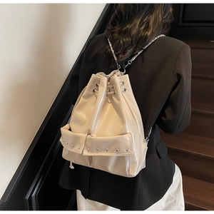 Detailed view of beige glossy leather bucket bag with silver studs and chain strap