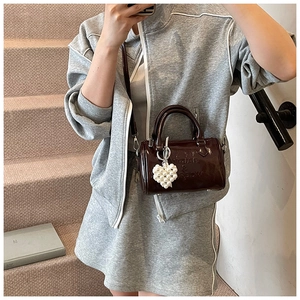 Mini borsa a cilindro in pelle verniciata rosso bruno scuro con ciondolo a cuore