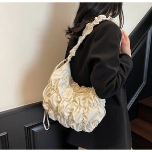 Detail view of cream cloud bag showing pleated texture and ruffled shoulder strap