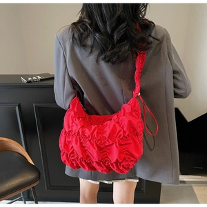 Detail view of red ruched hobo bag showing pleated texture and sleek nylon material