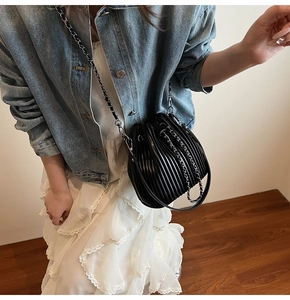 Macro shot of fashionable black pleated bucket bag with metallic chain strap detail