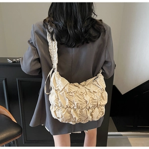 Detailed view of lightweight beige pleated dumpling bag worn by model on shoulder