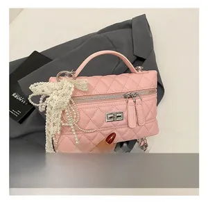 Detailed shot of pink quilted leather handbag with pearl tassels and lace bow