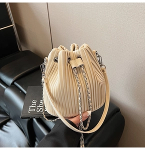 Close-up of pleated drawstring bucket bag with metal chain and leather strap details
