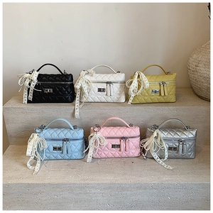 Close-up of six colorful quilted mini bags with metal handles and lace bows on steps