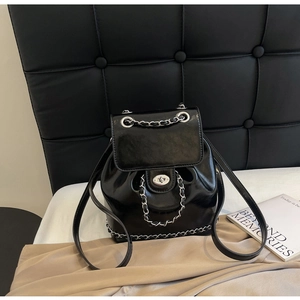 Detail of glossy black leather backpack with silver twist-lock and chain trim