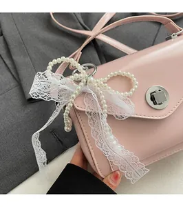 Détail du sac rose en similicuir avec nœud en perles, dentelle et fermoir rotatif argenté