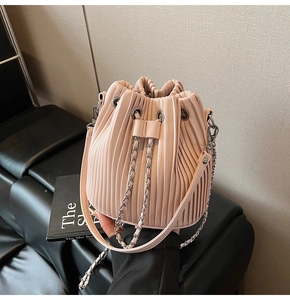Detail of pink pleated bucket bag showing drawstrings and silver chain shoulder strap