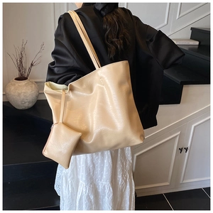 Detailed view of beige faux leather tote bag with matching small pouch in a modern setting