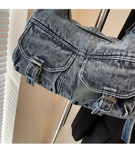 Close-up of blue denim tote bag showing twin pockets and metal buckle details