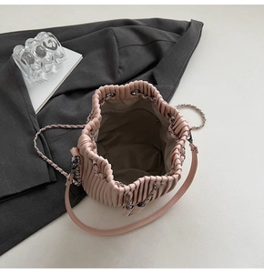 Close-up of pink pleated drawstring bucket bag with chain strap and leather handle