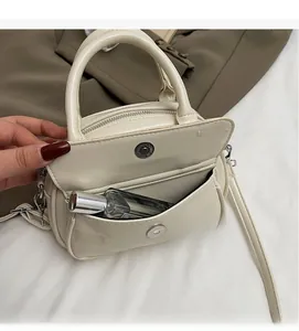Detail showing creamy white shoulder bag front pocket with perfume for storage capacity