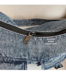Detail of silver metal zipper puller on blue washed denim motorcycle bag texture