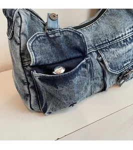Close-up of vintage washed denim tote bag with dual front utility pockets and zipper detail
